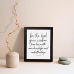 Proverbs 2:6 Christian wall art with black cursive text on a white background. For the Lord gives wisdom. displayed on the wall in a black frame