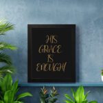 His Grace Is Enough Christian wall art in gold text on a black background, perfect for home decor and inspirational reminders. displayed on the wall in a black frame