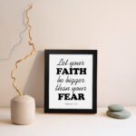 Let Your Faith Be Bigger Than Your Fear Hebrews 13:6 Christian Wall Art in black text on white background for home decor. displayed on the wall in a black frame