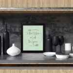 In This Kitchen We Lick The Spoon kitchen wall art with light green background and subtle kitchen utensil pattern in a casual handwritten font. displayed on the table