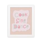 Cook Sing Dance Kitchen Wall Art with pastel pink, green, and blue text on a peach background, perfect for cheerful kitchen decor. displayed on the wall in a white frame in a white background