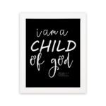 Black wall art with white text reading 'I am a CHILD of god' from John 1:12, showcasing a mix of cursive and bold lettering. hung on the wall in a white frame