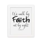 Christian wall art featuring the quote We walk by faith not by sight from Corinthians 5:7 in black text on a white background. hung on the wall in a white frame