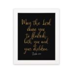 May The Lord Cause You To Flourish Both You And Your Children - Psalm 115:14 Christian Wall Art in golden text on black background. hung on the wall in a white frame