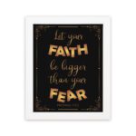 Infidu wall art with the text "Let your faith be bigger than your fear" in gold and bronze, with the Bible verse Hebrews 13:6 on a black background. hung on the wall in a white frame