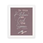 In This Kitchen We Lick The Spoon kitchen wall art with playful spoon illustration on a mauve background. displayed on the wall in a white frame in a white background