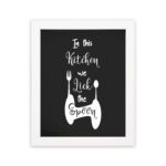 In This Kitchen We Lick The Spoon wall art with white cursive and bold fonts, black background, and stylish cutlery illustrations. displayed on the wall in a white frame in a white background