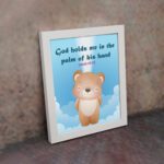 God Holds Me In The Palm Of His Hand Isaiah 49:16 Bible verse wall art for kids featuring a cartoon bear and fluffy clouds. displayed on the wall in a white frame