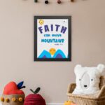 Wall art with the text Faith can move mountains from Matthew 17:20, featuring a sun rising over mountains. displayed on the wall in a black frame