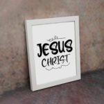 Jesus Christ wall art in black curly font on a white background, showcasing elegant Christian design. displayed on the wall in a white frame