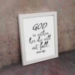 God Is Within Her, She Will Not Fall Psalm 46:5 Christian wall art with black lettering on a white background. displayed on the wall in a white frame