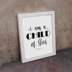 I Am A Child of God John 1:12 Christian Wall Art with black text on a white background displayed on the wall in a white frame