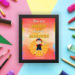 Colorful wall art featuring a happy child holding a heart with the quote You Are Loved Beyond Measure and Romans 8:38. displayed on the wall in a black frame in a colorful background