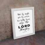 Not By Might Nor By Power Zechariah 4:6 Christian wall art with black text on a white background. displayed on the wall in a white frame