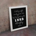 Not By Might Nor By Power Zechariah 4:6 Christian wall art with white text on a black background. displayed on the wall in a white frame