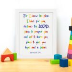 Colorful wall art featuring Jeremiah 29:11, For I Know The Plans I Have For You, with rainbow text on a white background. displayed on the table in a white frame