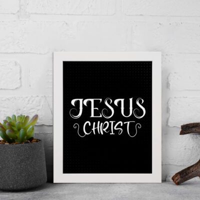 Jesus Christ wall art in white curly font on a black background, showcasing elegant Christian design. displayed on the wall in a white frame