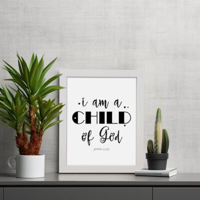 I Am A Child of God John 1:12 Christian Wall Art with black text on a white background displayed on the table in a white frame