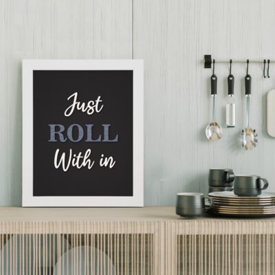 Just Roll With It kitchen wall art with white and blue text on a black background, framed in black for a modern, minimalist look. displayed on the table