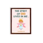 Infidu wall art featuring a cute angel with pink wings and a light blue dress, with the text The Spirit of God lives in me above. hung on the wall in a brown frame