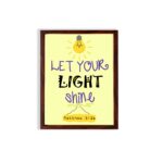 Infidu wall art featuring a lightbulb and the verse Let Your Light Shine from Matthew 5:16 in colorful fonts on a yellow background. hung on the wall in a brown frame