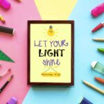 Infidu wall art featuring a lightbulb and the verse Let Your Light Shine from Matthew 5:16 in colorful fonts on a yellow background. displayed on the wall in a brown frame in a colorful background