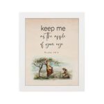 Psalm 17:8 wall art with a soft cursive font and a peaceful illustration of a person sitting under a tree. Wall Art hung on the wall in white frame