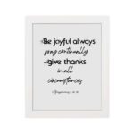 Infidu wall art with the text Be joyful always, pray continually, give thanks in all circumstances from 1 Thessalonians 5:16-18. hung on the wall in a white frame