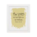 The Lord My God Lights Up My Darkness Psalm 18:28 Bible Verse Wall Art with decorative text on a light yellow paint stroke background. Wall Art hung on the wall in white frame