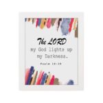 The Lord My God Lights Up My Darkness Psalm 18:28 Bible Verse Wall Art with black text and bold red, orange, blue, and yellow brush strokes on a white background. Wall Art hung on the wall in a white frame