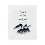 Infidu Trust In The Lord And Do Good Psalm 37:3 Bible Wall Art with black text and mountain illustration. Wall Art hung on the wall in a white frame