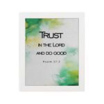 Trust in the Lord and Do Good Psalm 37:3 Bible Verse Wall Art with watercolor green and yellow background. Wall Art hung on the wall in white frame