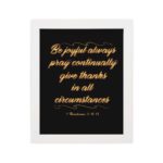 Bible verse wall art featuring 1 Thessalonians 5:16-18 in gold cursive text on a solid black background, arranged in a stacked format. hung on the wall in a white frame