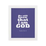 Be Still and Know That I Am God Psalm 46:10 Christian Wall Art with bold white text on a dark purple background. Wall Art hung on the wall in a white frame