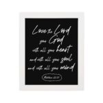 Matthew 22:37 Bible wall art with white text on a black background, reading Love the Lord your God with all your heart. hung on the wall in a white frame