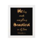 Ecclesiastes 3:11 wall art with golden text on a black background saying He Has Made Everything Beautiful In Its Time. hung on the wall in white frame