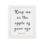 Keep Me As The Apple Of Your Eye Psalm 17:8 black text in cursive on a white background, framed in black hung on the wall in a white frame- Christian wall art