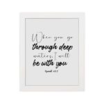 White wall art with black text in script and bold fonts quoting When you go through deep waters, I will be with you from Isaiah 43:2. hung on the wall in a white frame