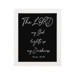 The Lord My God Lights Up My Darkness Psalm 18:28 white handwritten text on black background Christian wall art hung on the wall in a white frame