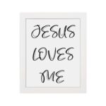 Jesus Loves Me Bible wall art with black script text on a white background. Wall Art hung on the wall in a white frame