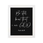 Be Still and Know That I Am God - Psalm 46:10 Bible Verse Wall Art with White Cursive Text on Black Background Wall Art hung on the wall in a white frame