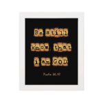 Be Still and Know That I Am God - Psalm 46:10 Bible Verse Wall Art with Scrabble-like Letters on Dark Background Wall Art hung on the wall in a white frame