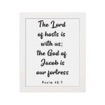 The Lord Of Hosts Is With Us - Psalm 46:7 Bible Verse Wall Art with White Text on Light Background Framed in Black Wall Art white on the wall in black frame