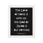 The Lord Of Hosts Is With Us - Psalm 46:7 Bible Verse Wall Art with White Text on Black Background Wall Art hung on the wall in a white frame