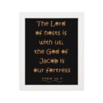 The Lord Of Hosts Is With Us - Psalm 46:7 Bible Verse Wall Art with Golden Text on Black Background Wall Art hung on the wall in a white frame