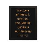 The Lord Of Hosts Is With Us - Psalm 46:7 Bible Verse Wall Art with Golden Text on Black Background Wall Art hung on the wall in a black frame