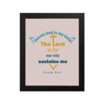 Surely God Is My Help - Psalm 54:4 Bible Verse Wall Art with Colorful Fonts and Cross Symbol on Soft light pink Background Wall Art hung on the wall in a black frame