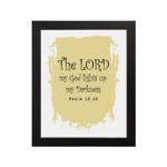 The Lord My God Lights Up My Darkness Psalm 18:28 Bible Verse Wall Art with decorative text on a light yellow paint stroke background. Wall Art hung on the wall in black frame