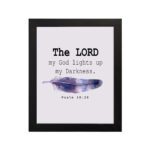 The Lord My God Lights Up My Darkness Psalm 18:28 Bible Verse Wall Art with black text and a purple and blue feather on a white background. Wall Art hung on the wall in a black frame