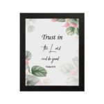 Trust in the Lord and Do Good Psalm 37:3 Bible Wall Art with botanical green leaves and pink flowers on a white background. Wall Art hung on the wall in a black frame